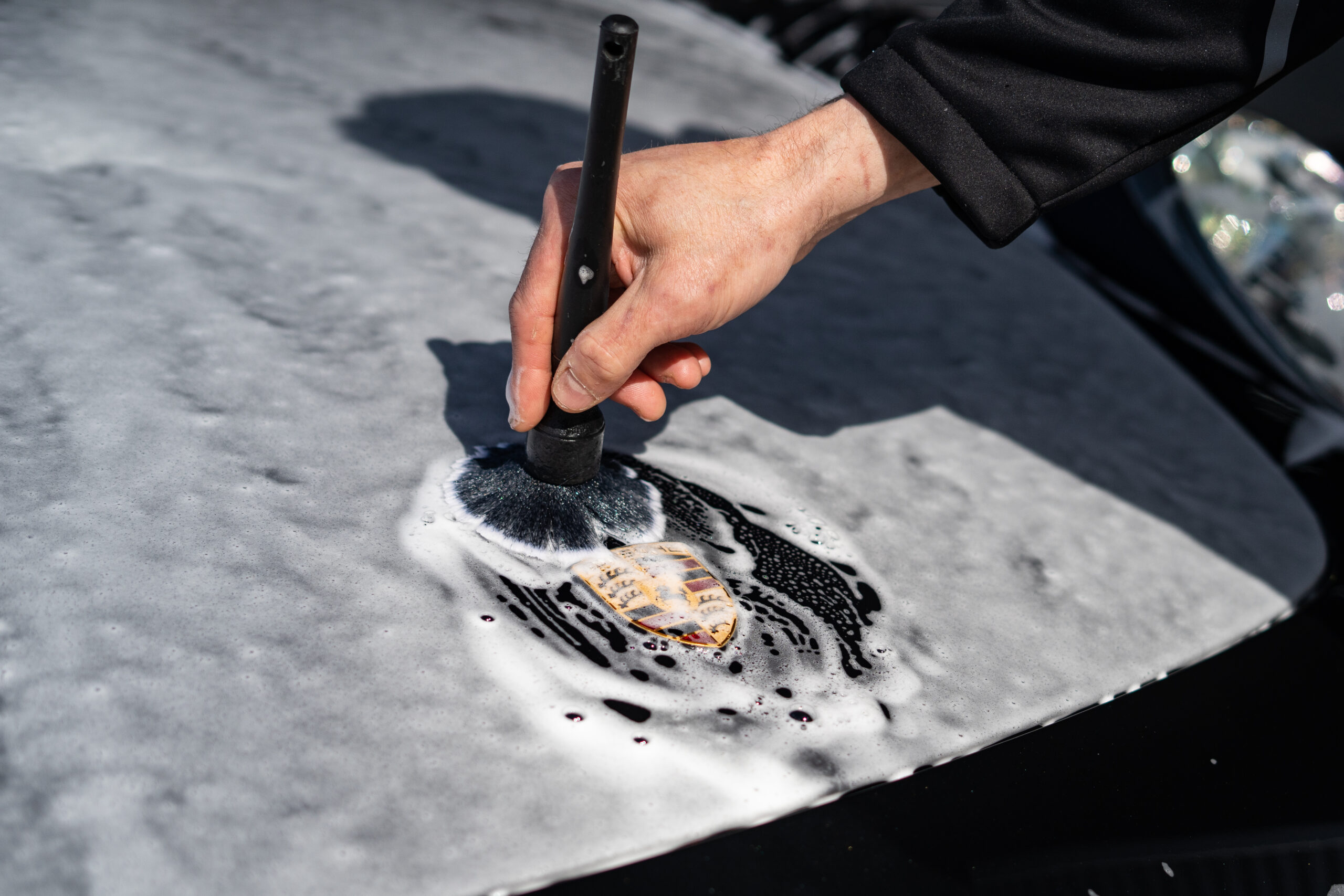 Porsche-embleem reinigen met een detailingkwast en schuim